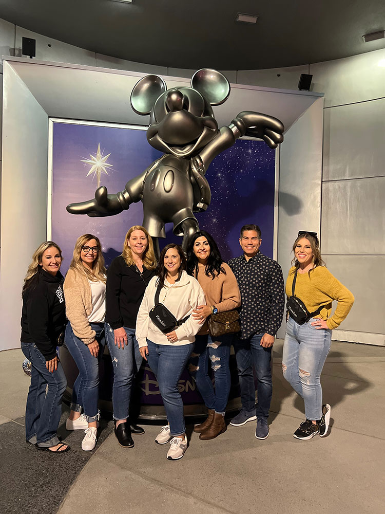 Staff in front of a statue of Mickey Mouse